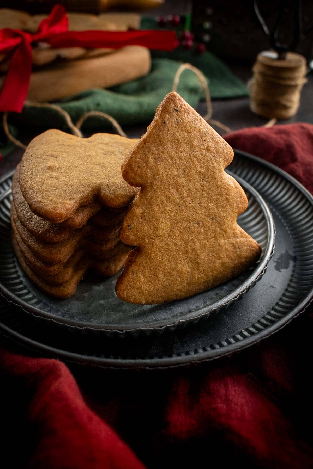 Tree-shaped brown cookies stacked on a metal plate.