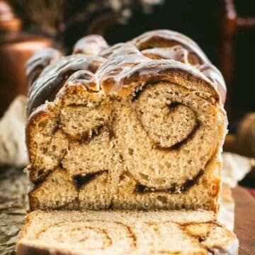 A loaf of bread with cinnamon swirled inside and white glaze on top.