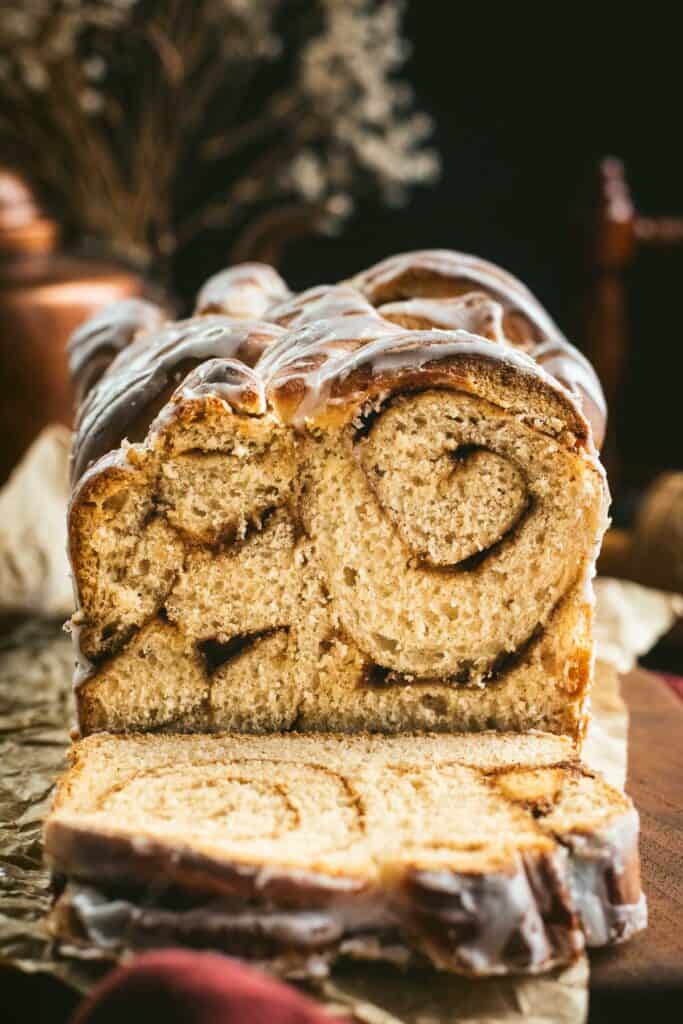A loaf of bread with cinnamon swirled inside and white glaze on top.