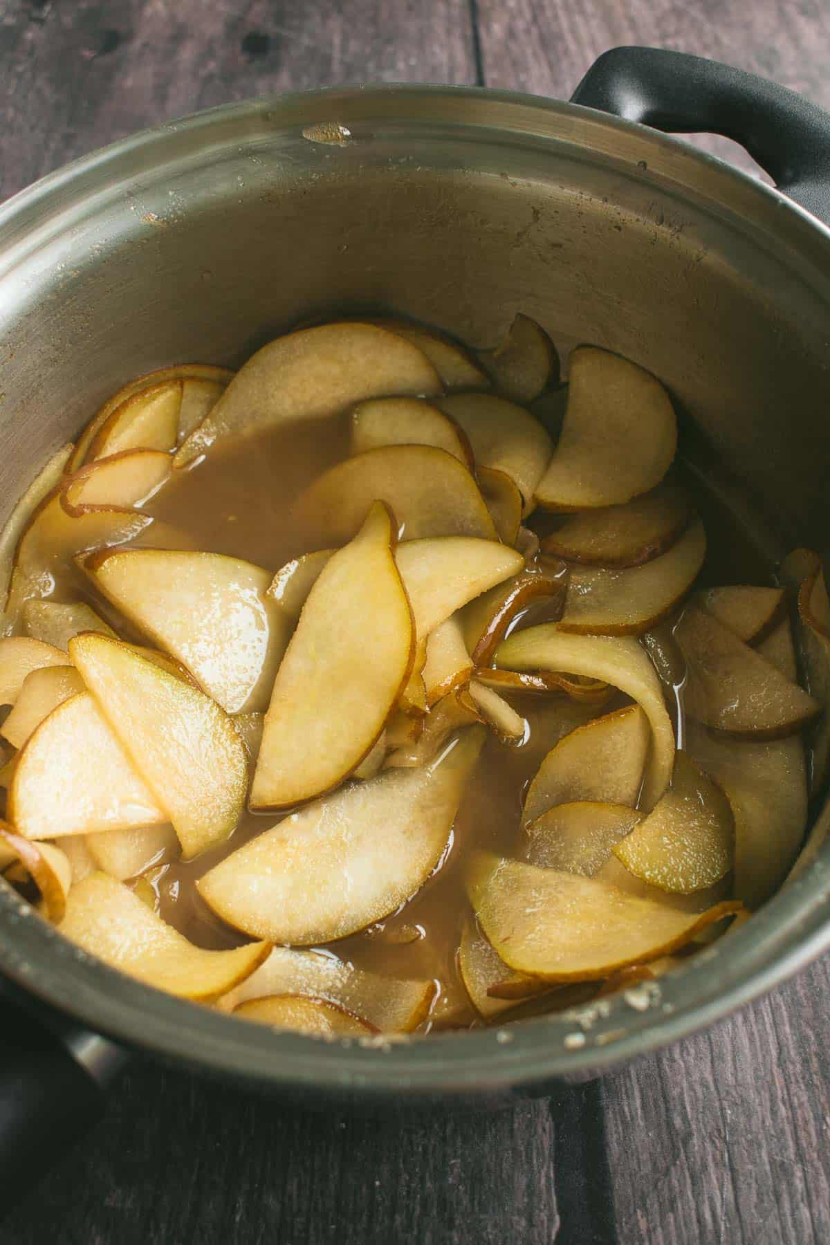Sliced pears cooking in butter and brown sugar in a saucepan.