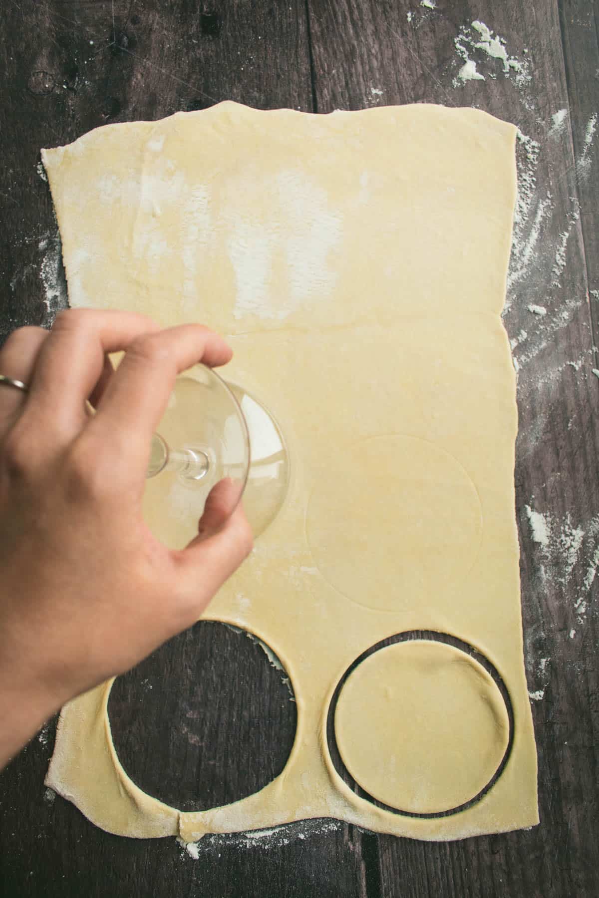 A hand cutting out circles from pastry dough.