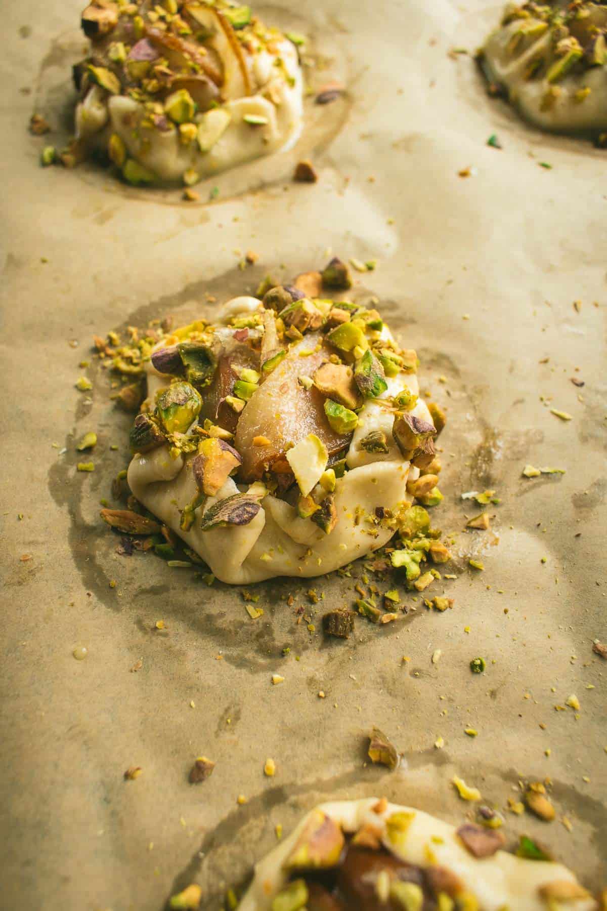 Unbaked pear tarts covered in chopped nuts.