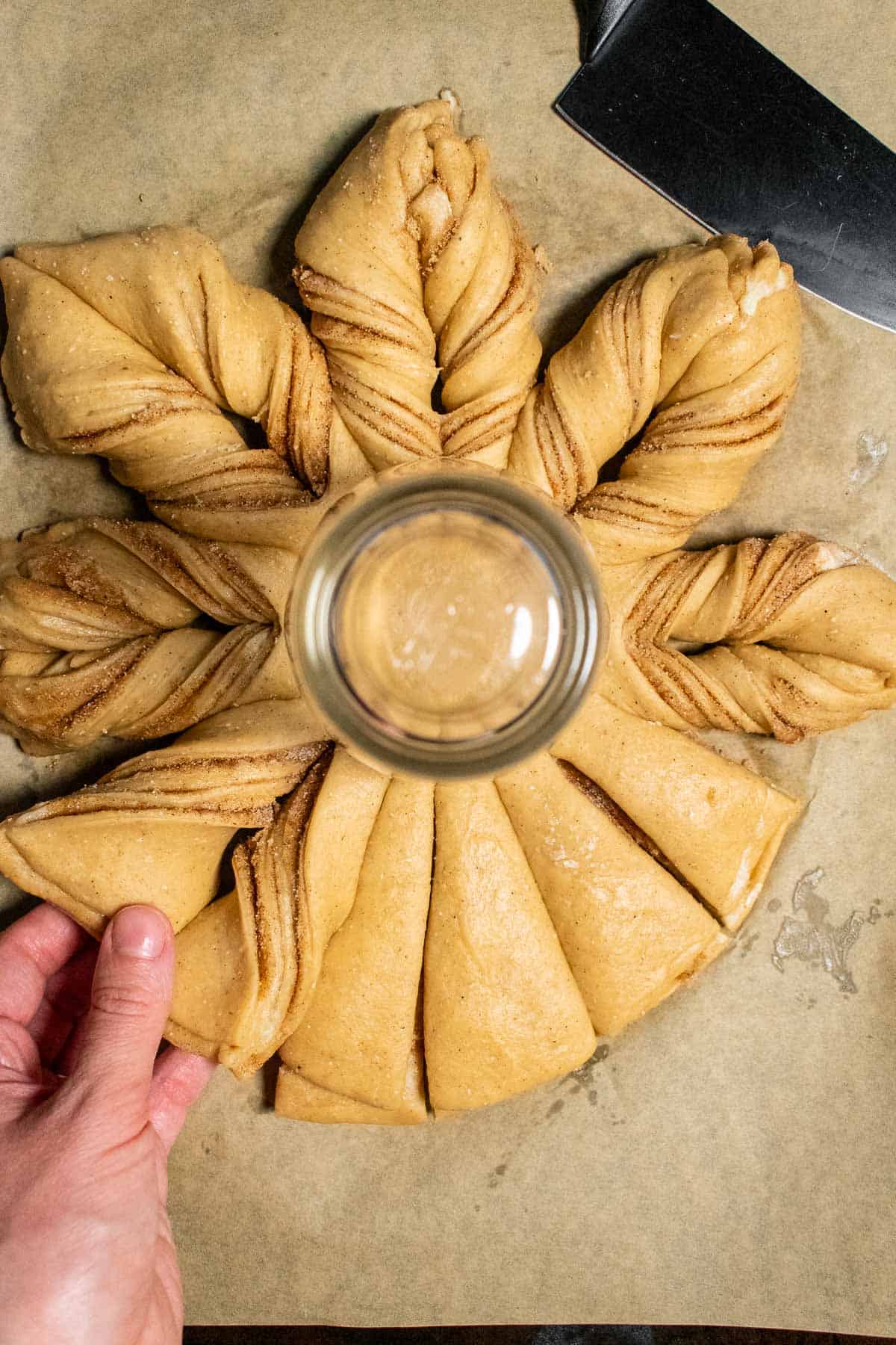 Stacked dough and cinnamon sugar being cut and twisted.