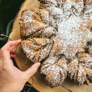 A hand picking up a piece of twisted cinnamon bread.
