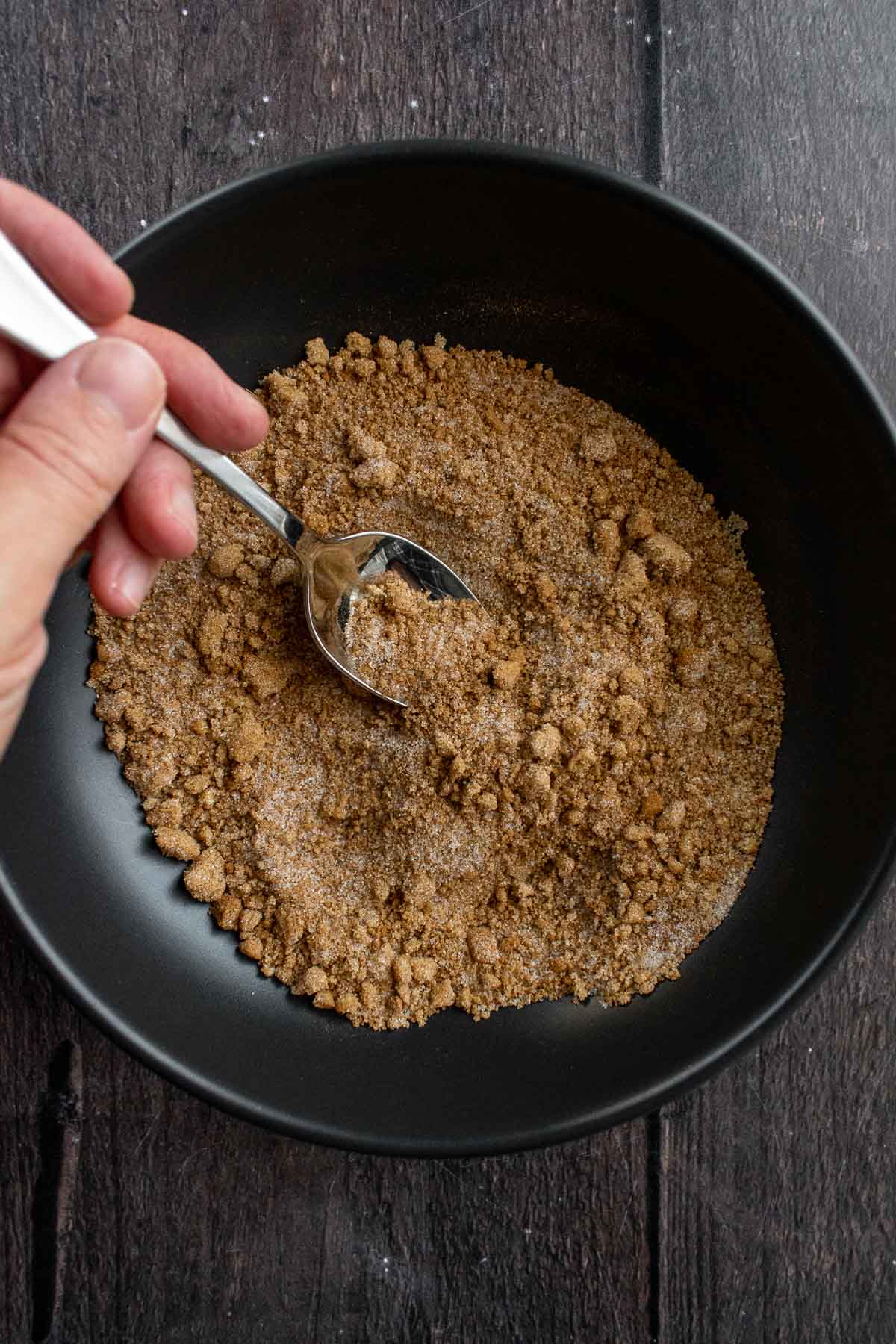 Cinnamon and sugar mixed in a bowl with a spoon.