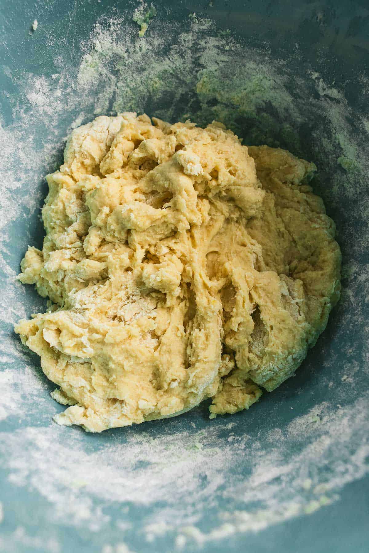 A light yellow bread dough in a blue mixing bowl.