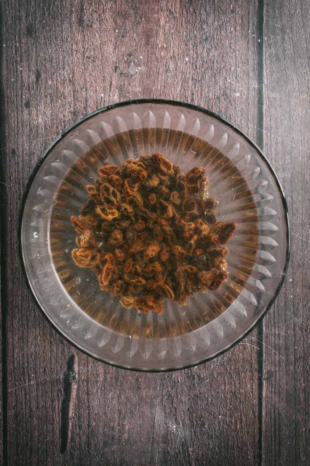 Raisins soaking in water in a bowl.