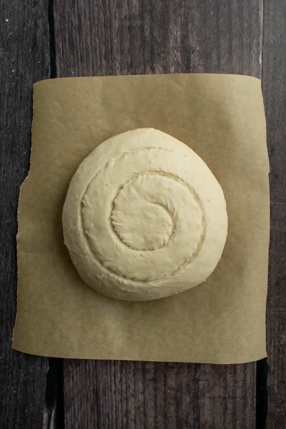 A ball of bread dough scored with a spiral on top.