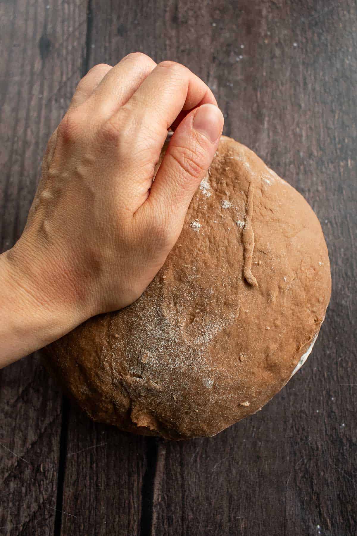A hand kneading a ball of chocolate dough.