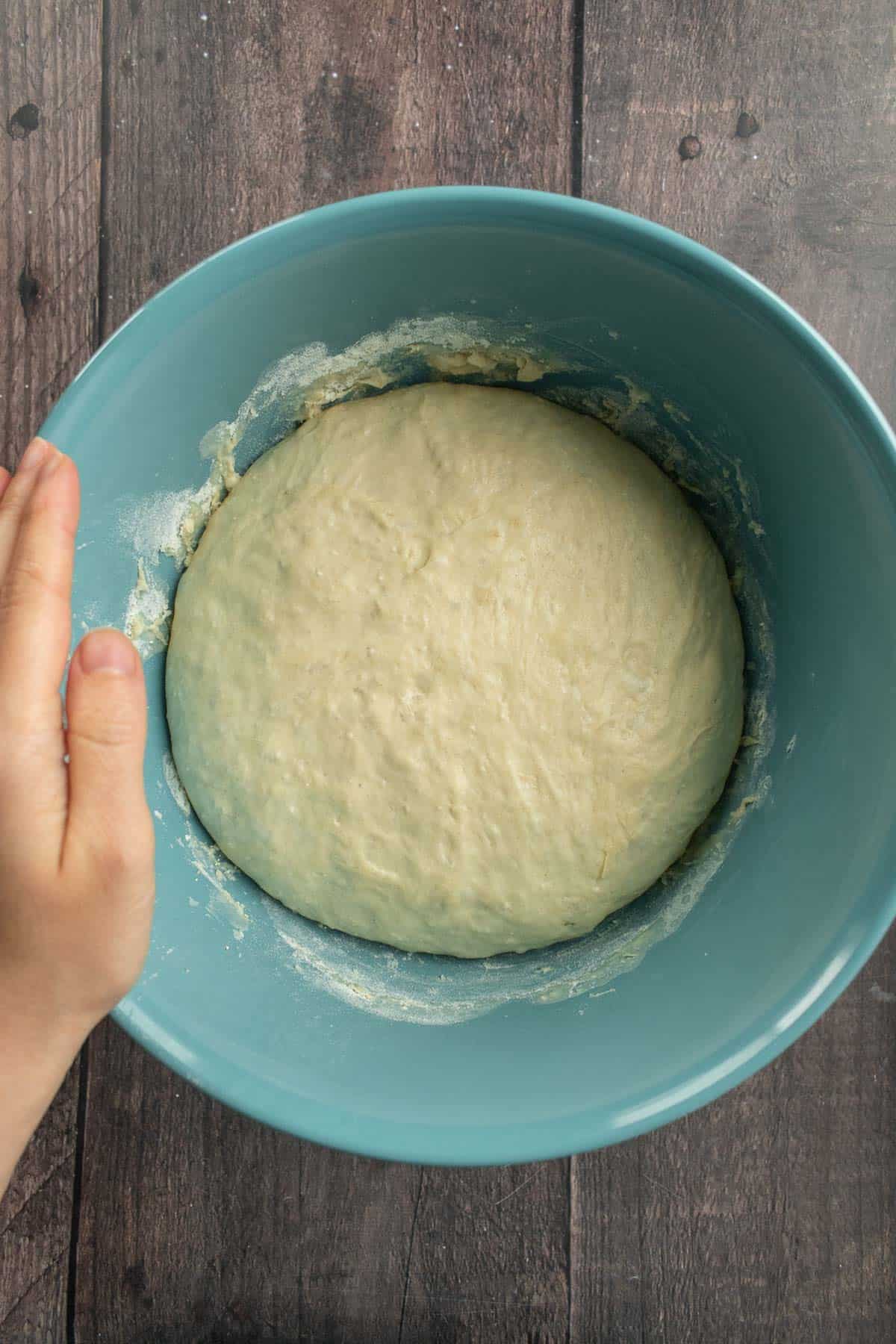 Risen bread dough in a large blue bowl.