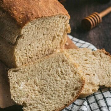 Two slices of white bread next to the rest of the cut loaf.
