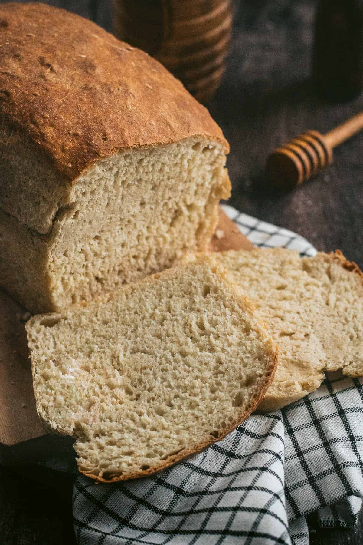 Two slices of white bread next to the rest of the cut loaf.