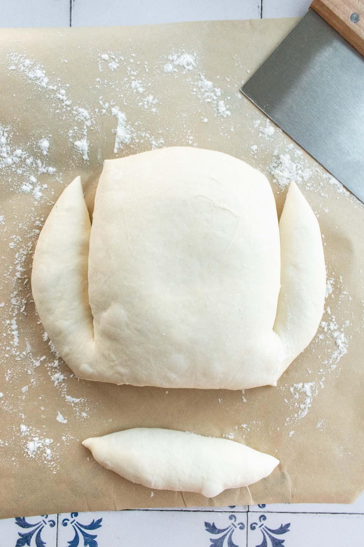 A boule of bread dough with the bottom cut off and two more cuts made into the sides.