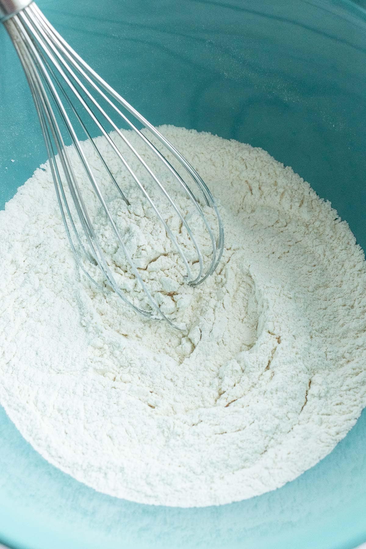 A whisk in a bowl of flour.