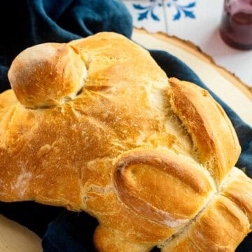 Golden, crusty bread baked in the shape of a bunny on a blue linen.