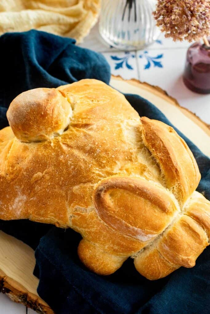 Golden, crusty bread baked in the shape of a bunny on a blue linen.