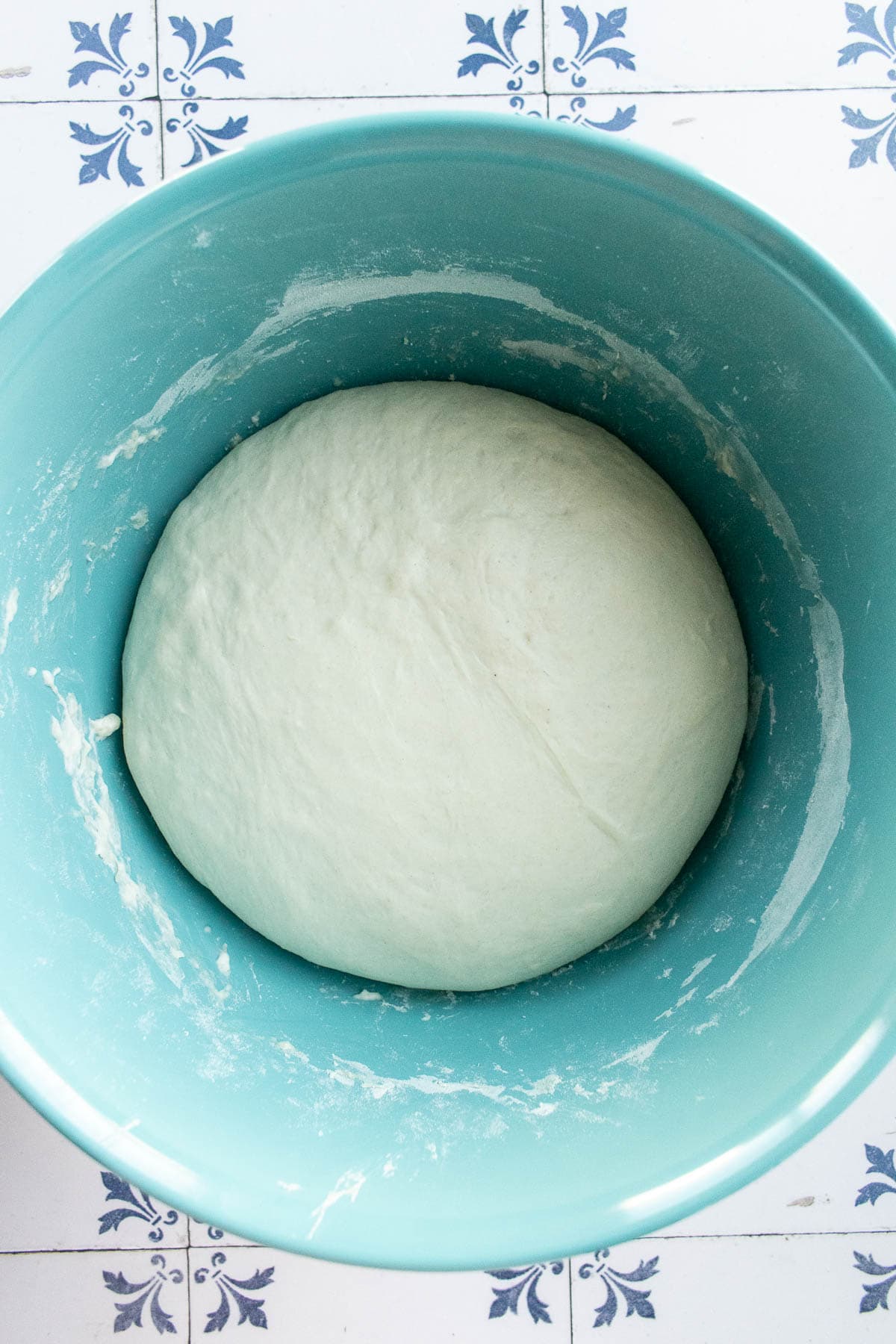 Risen white bread dough in a blue bowl.