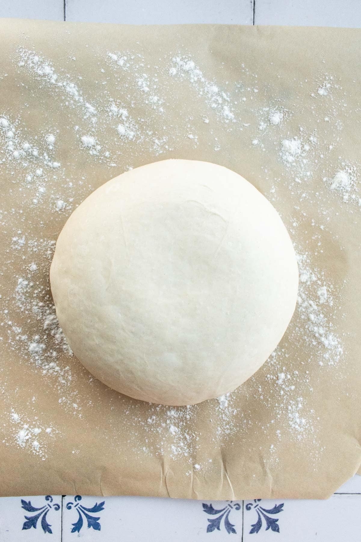 A boule of bread dough on a flour-lined piece of parchment paper.