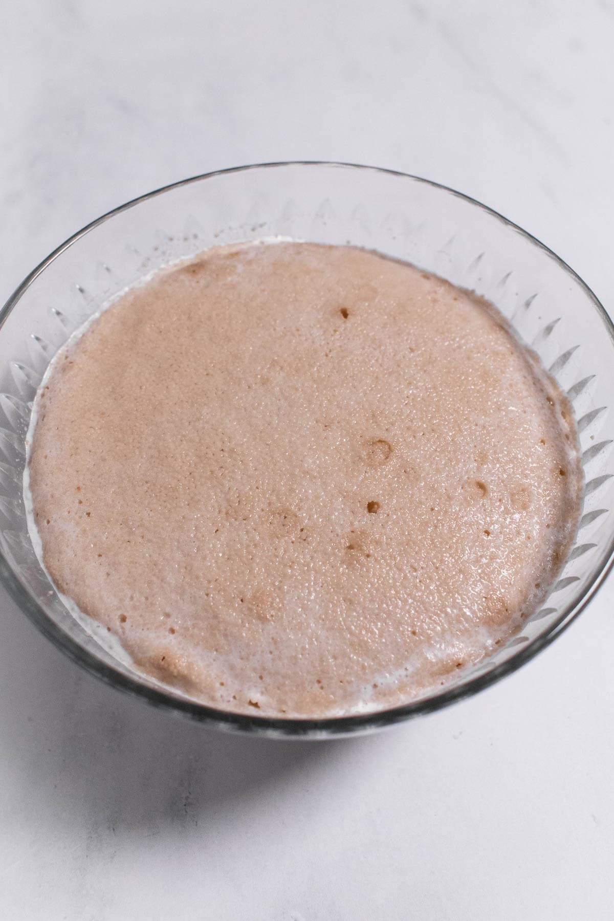 Frothy yeast and milk in a glass bowl.