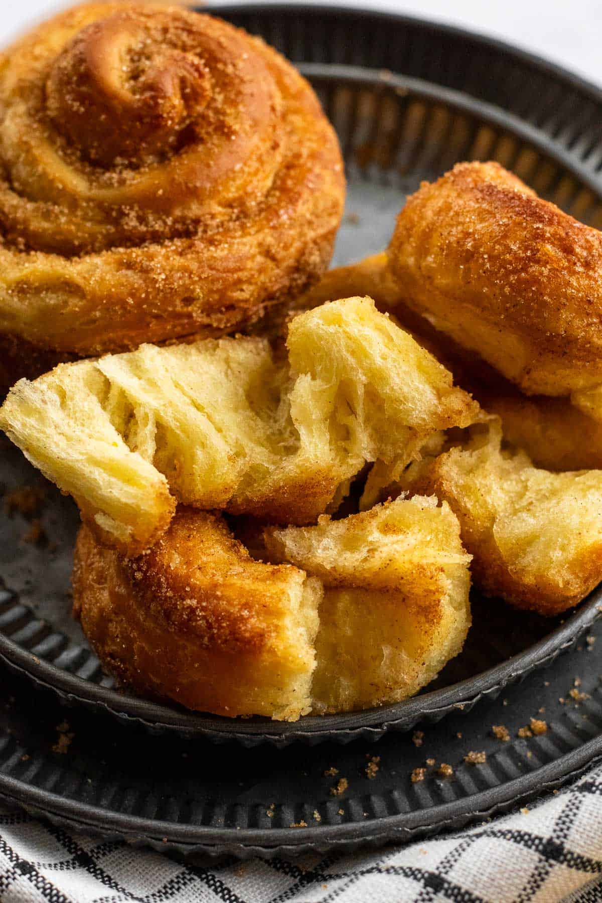 Flaky layers of a half-eaten morning bun on display on a metal plate.
