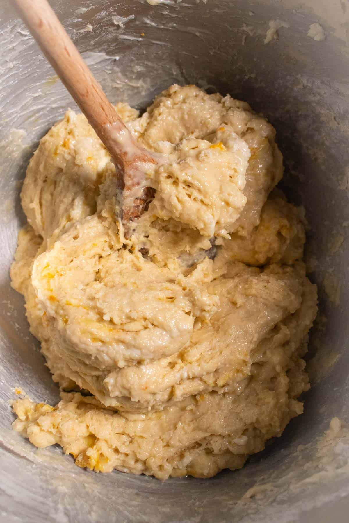 A tacky bread dough in a bowl with a wooden spoon.