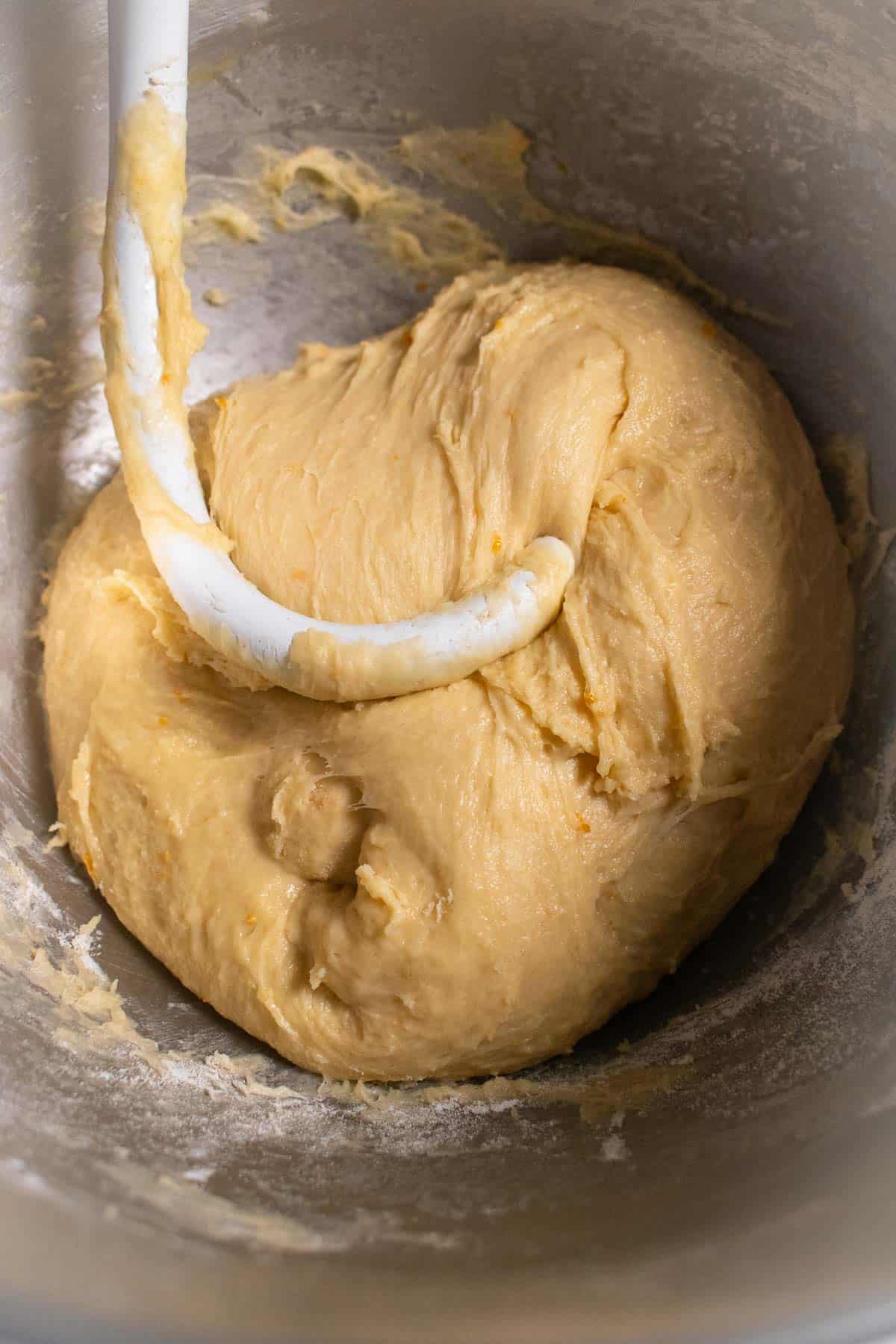 Kneaded bread dough in a bowl with a dough hook.