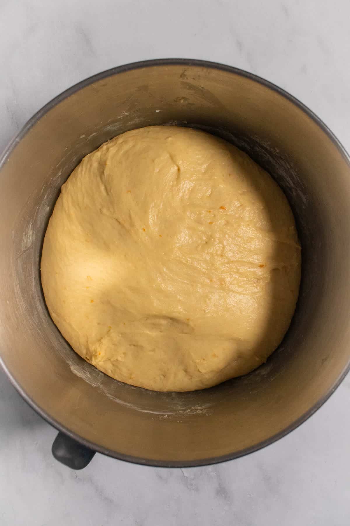 Risen enriched dough in a large mixing bowl.