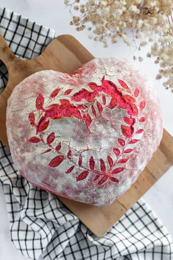 A pink heart-shaped loaf of bread on a cutting board.