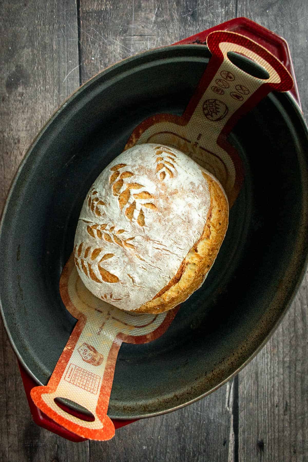 A baked loaf of crispy bread in a Dutch oven.