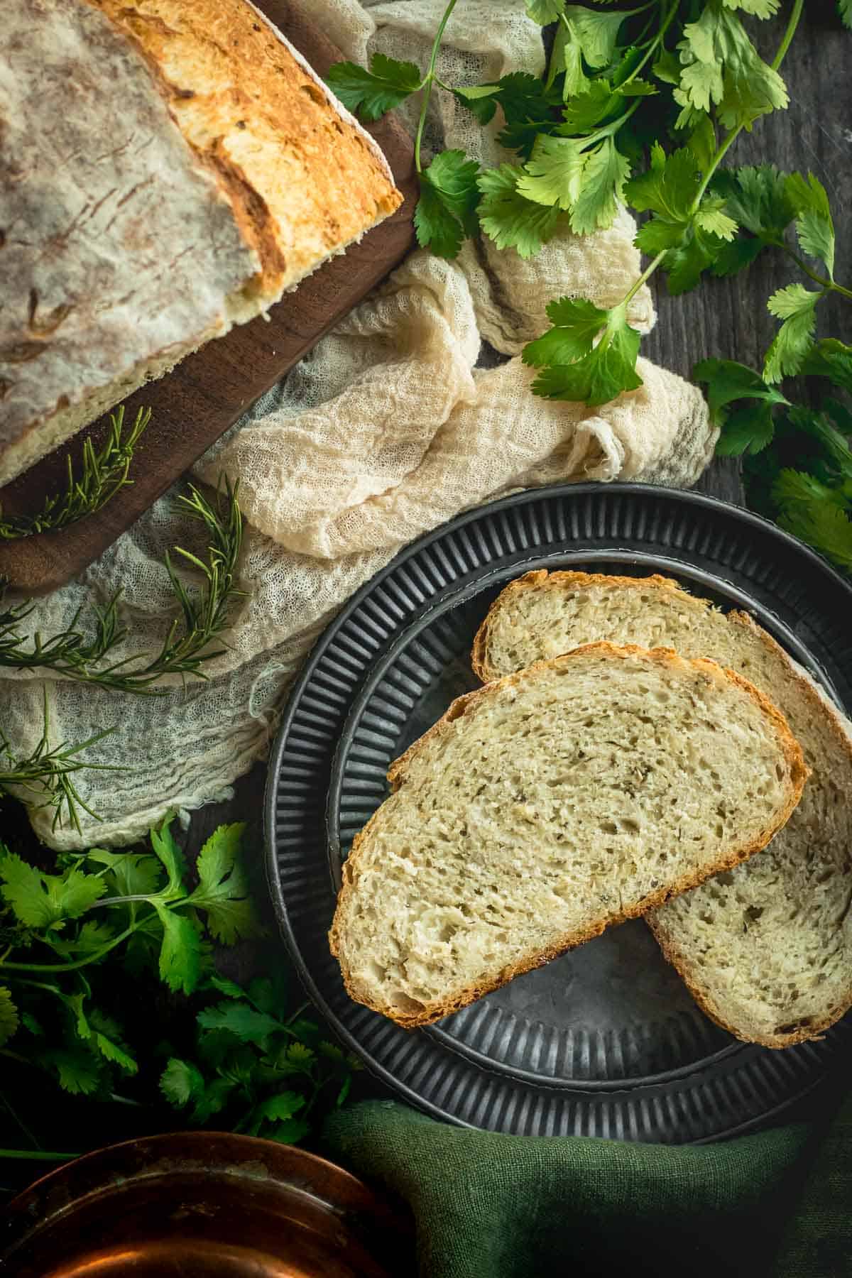 Two slices of herb bread on stacked metal plates.