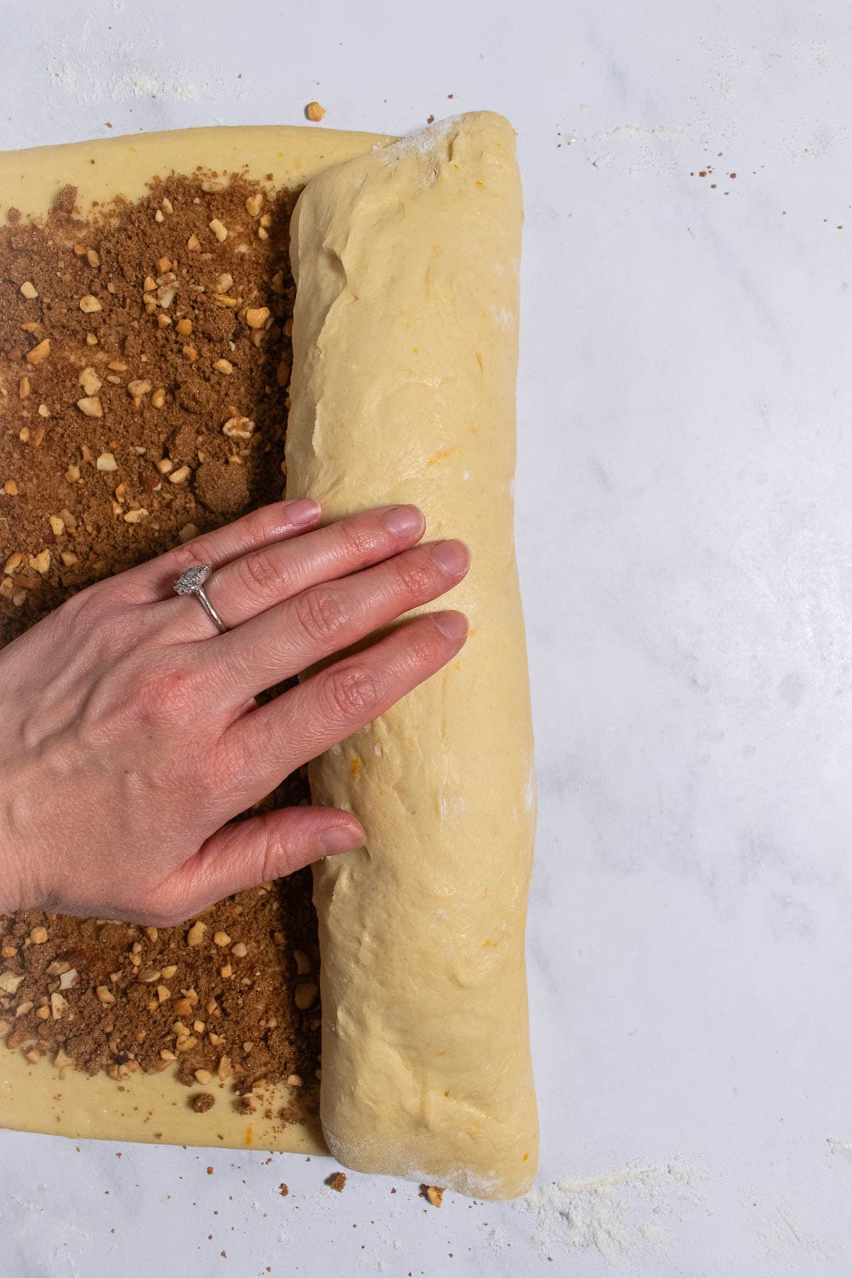 A hand rolling up cinnamon roll dough into a log.
