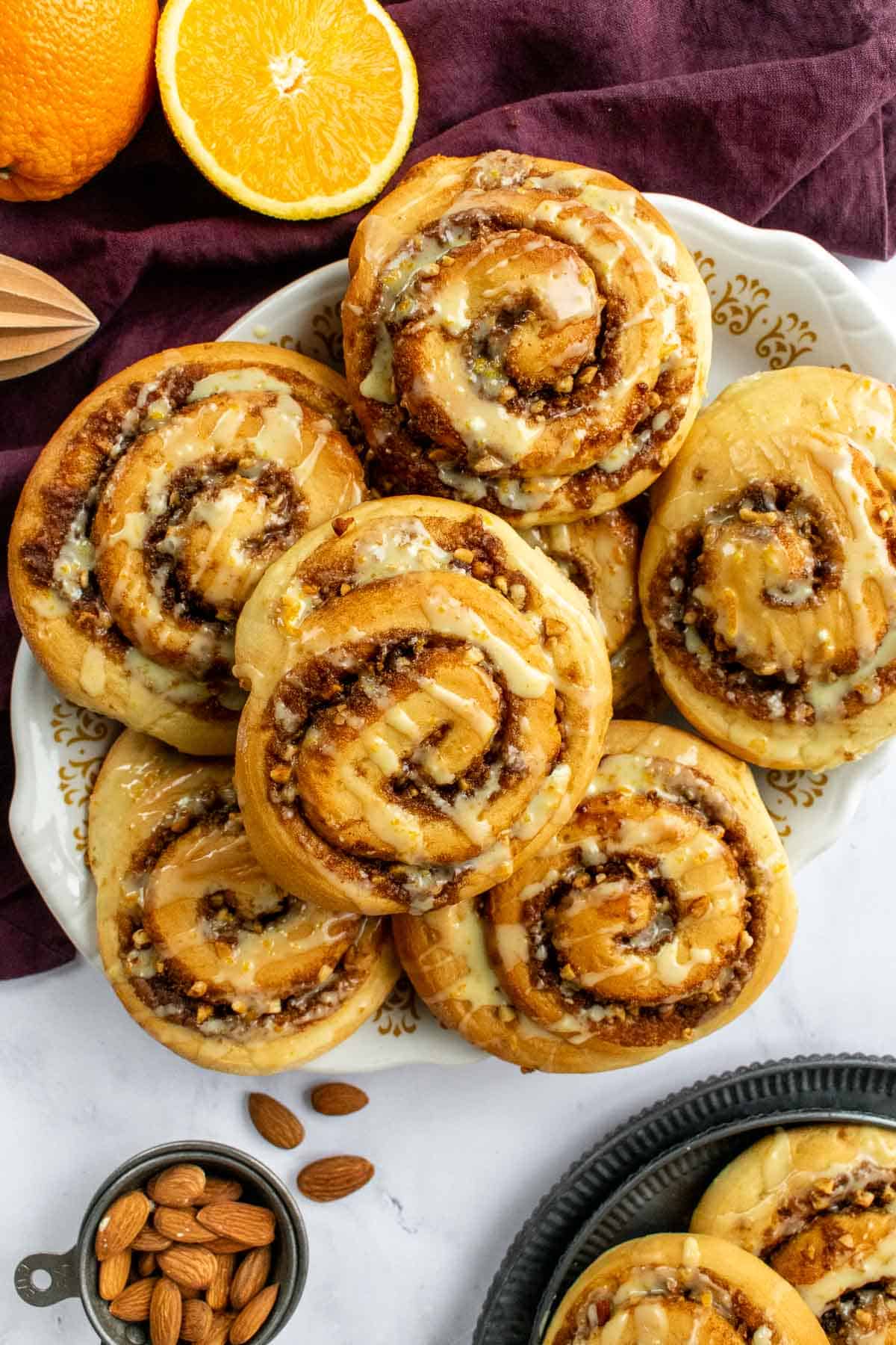 Seven orange cinnamon rolls piled on a white serving platter.