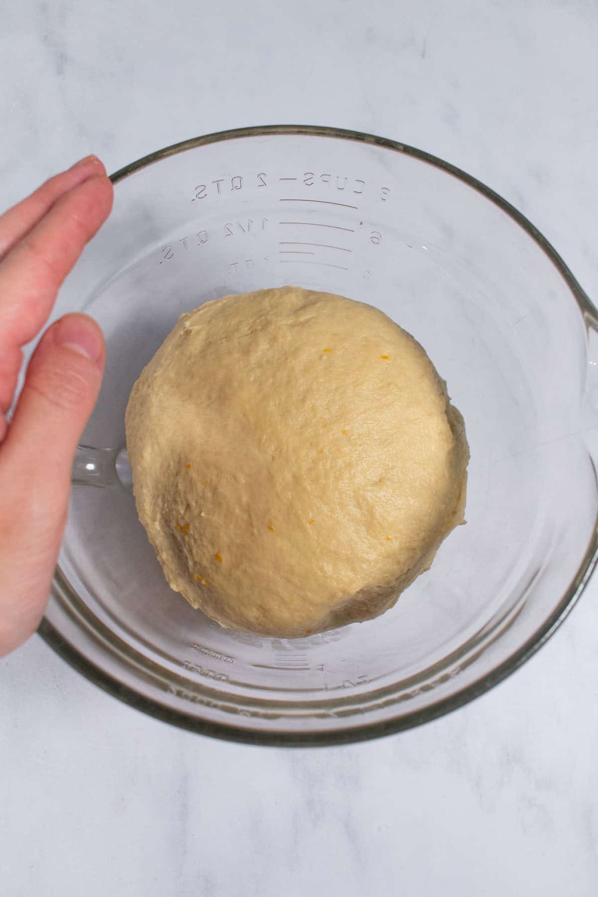 A small ball of enriched bread dough in a glass bowl.