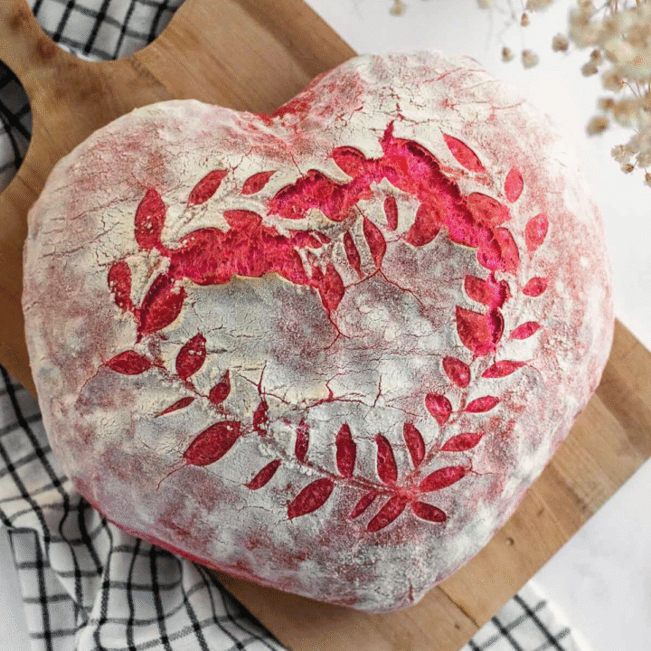 Pink bread shaped like a heart on a wooden board. on a linen.