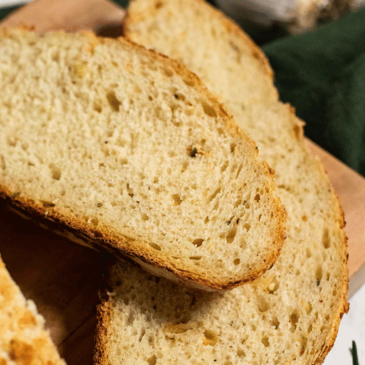 Two slices of crusty garlic bread on a wooden board.