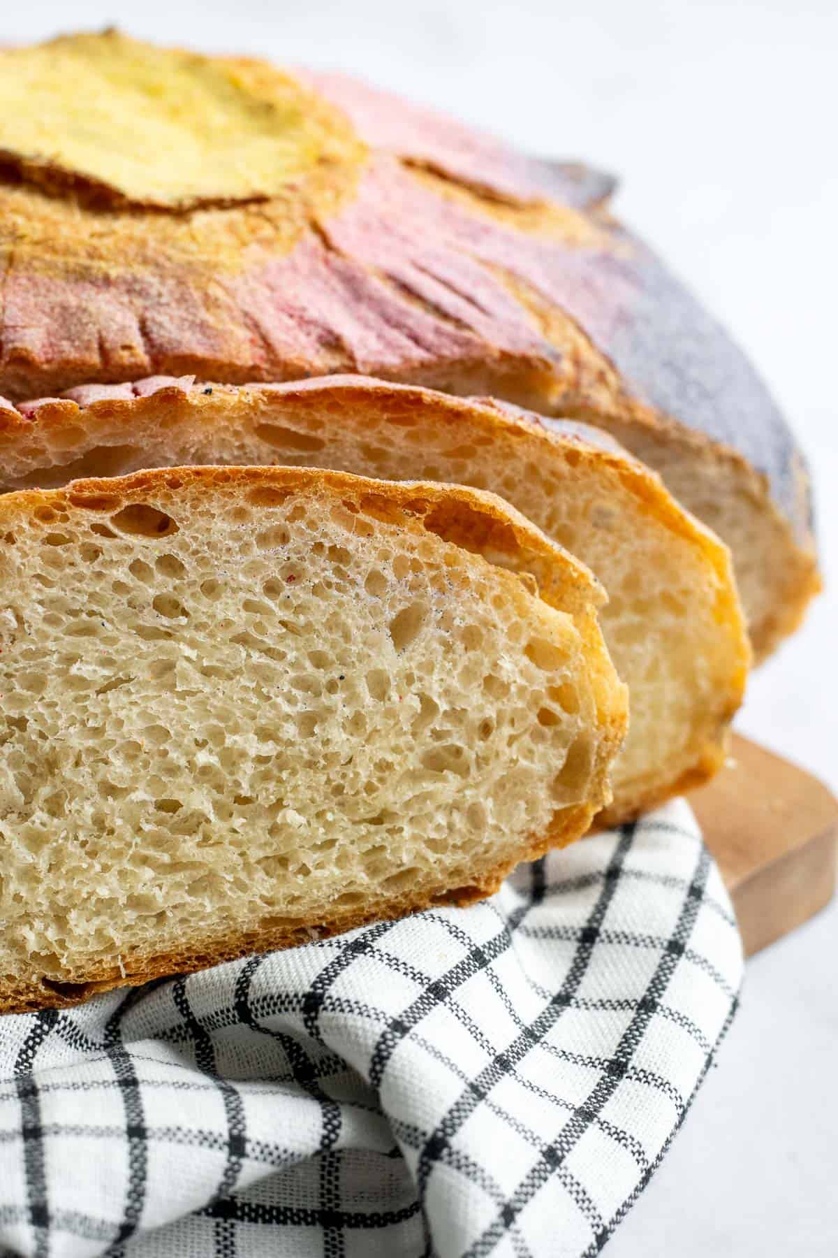Slices of airy, white, rustic bread on a black and white linen.