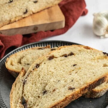 Two slices of artisan bread filled with chopped olives on a metal plate.