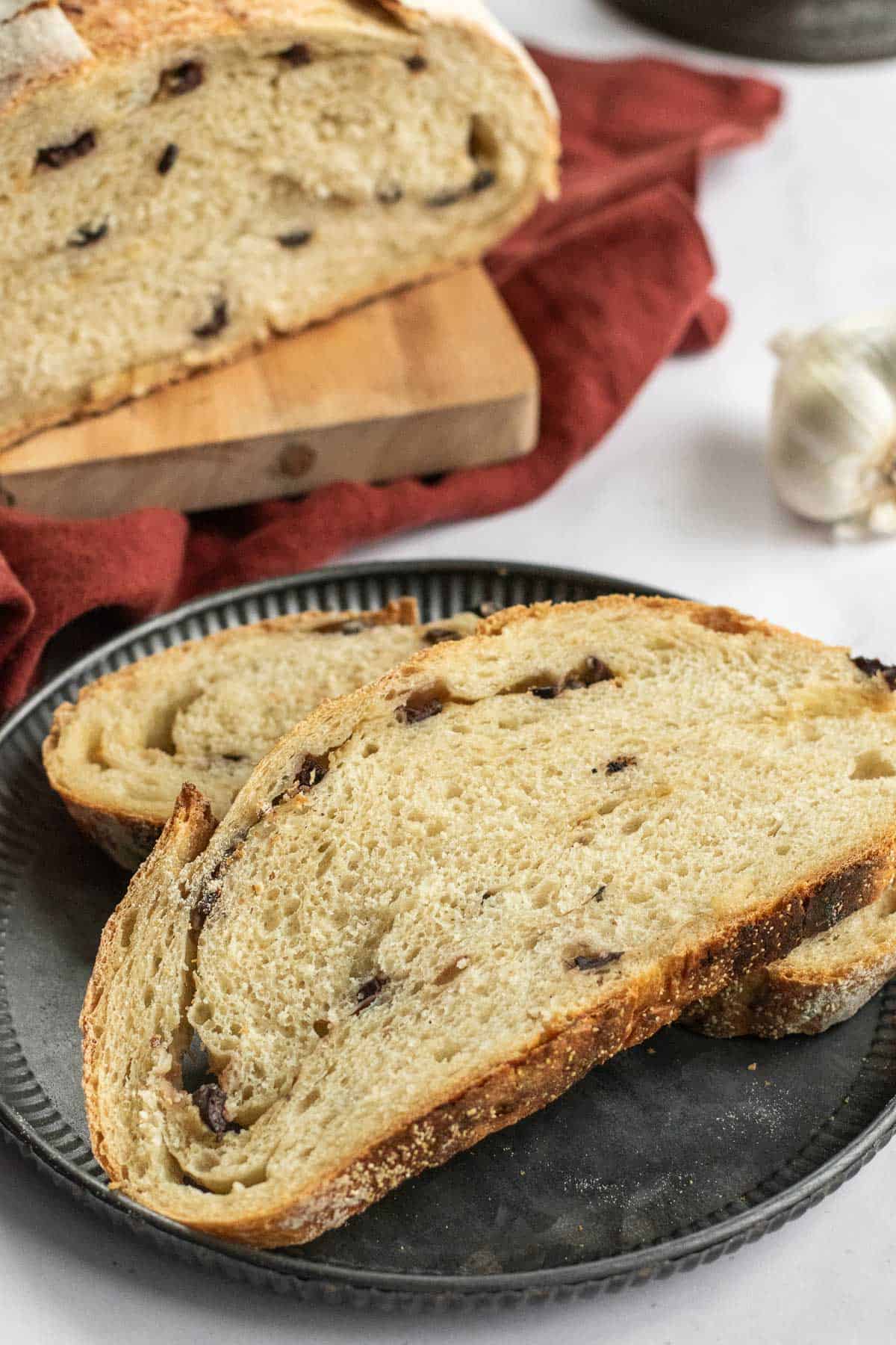 Two slices of artisan bread filled with chopped olives on a metal plate.
