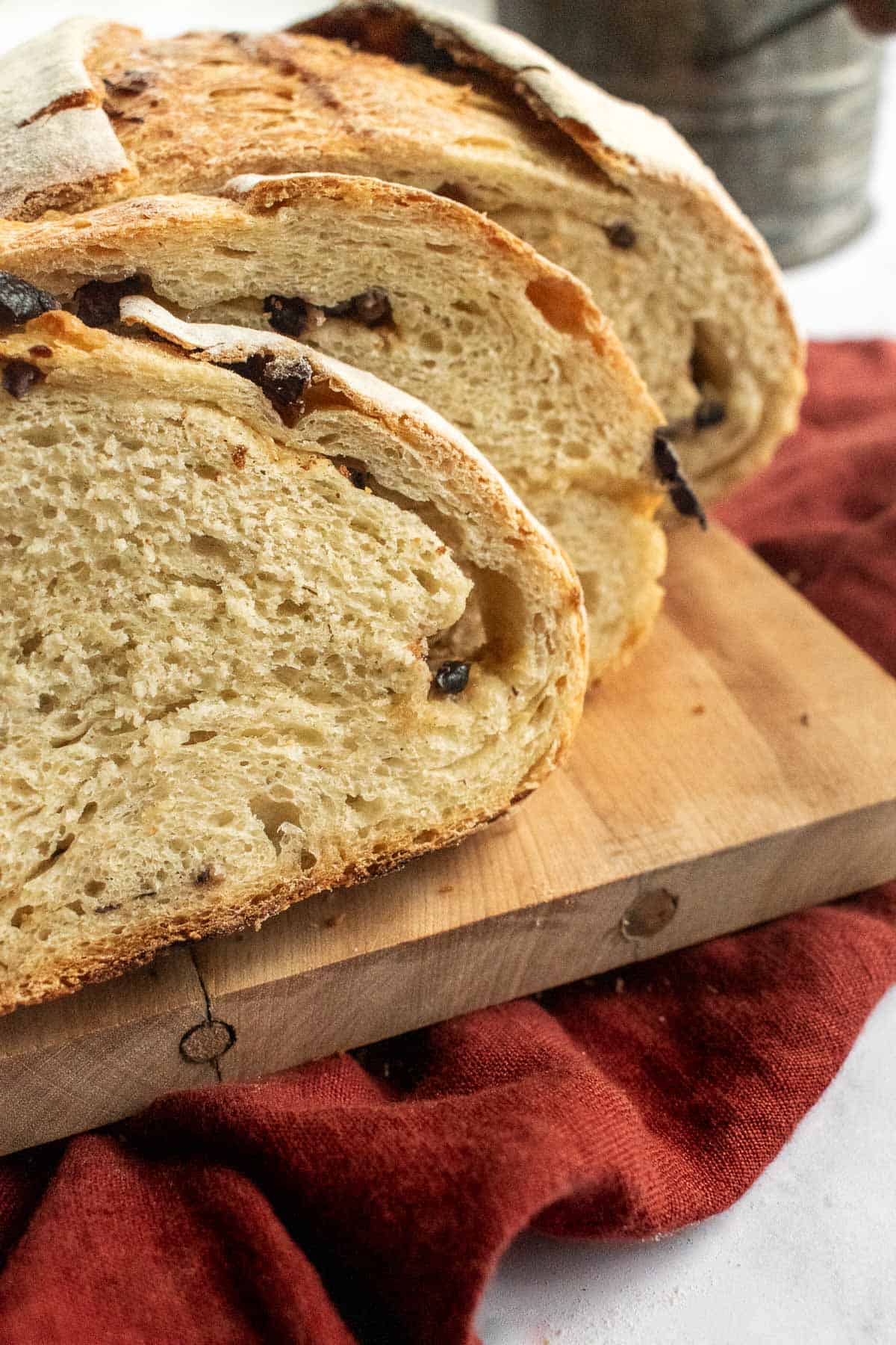 Slices of olive and garlic-filled rustic bread on a wooden cutting board.