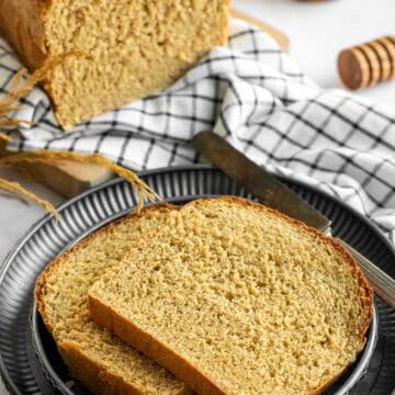 Two slices of wheat sandwich bread on stacked metal plates.