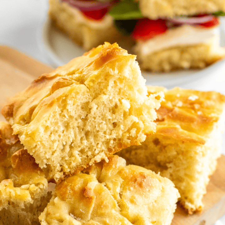 Slices of fluffy focaccia on a cutting board topped with flaky sea salt.
