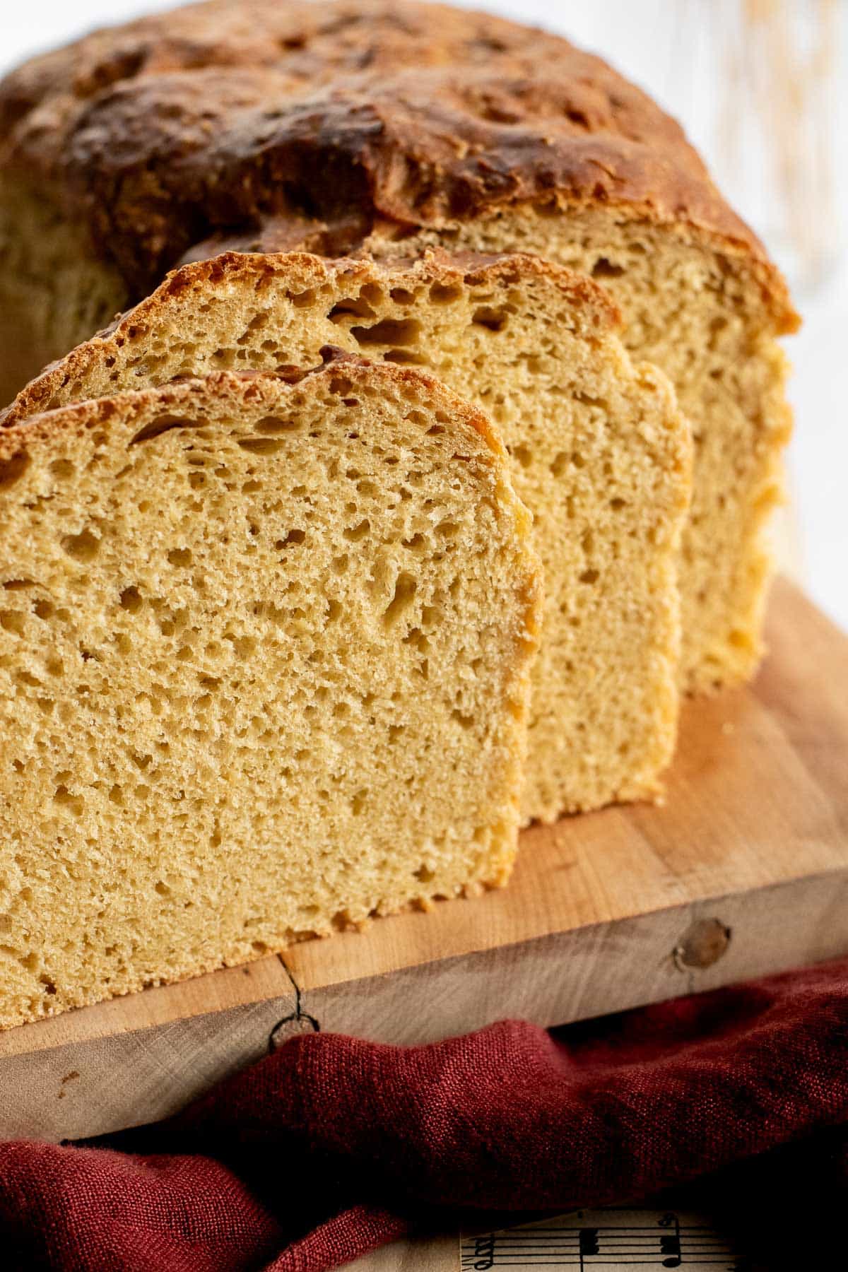 Two slices of light brown sandwich bread next to the rest of the loaf on a wooden board.