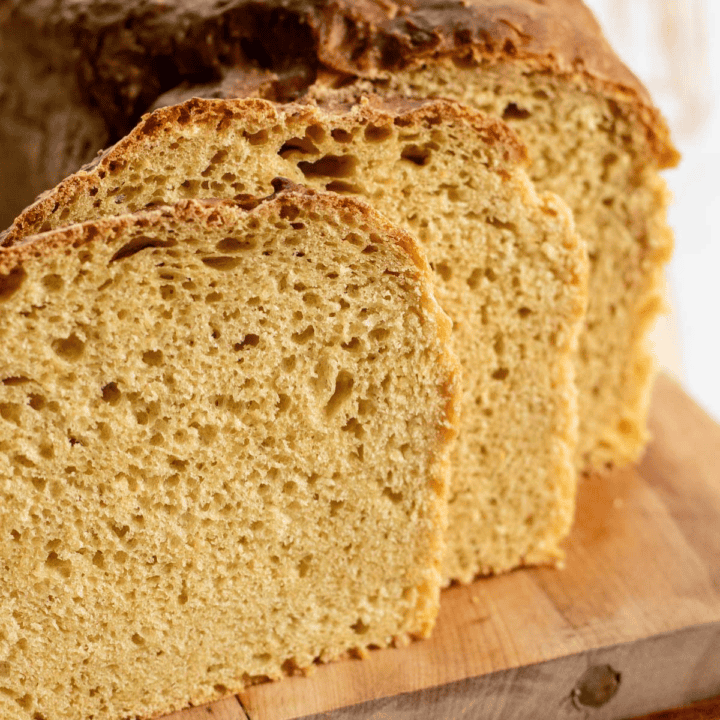 Slices of einkorn sandwich bread on a cutting board on a light surface.