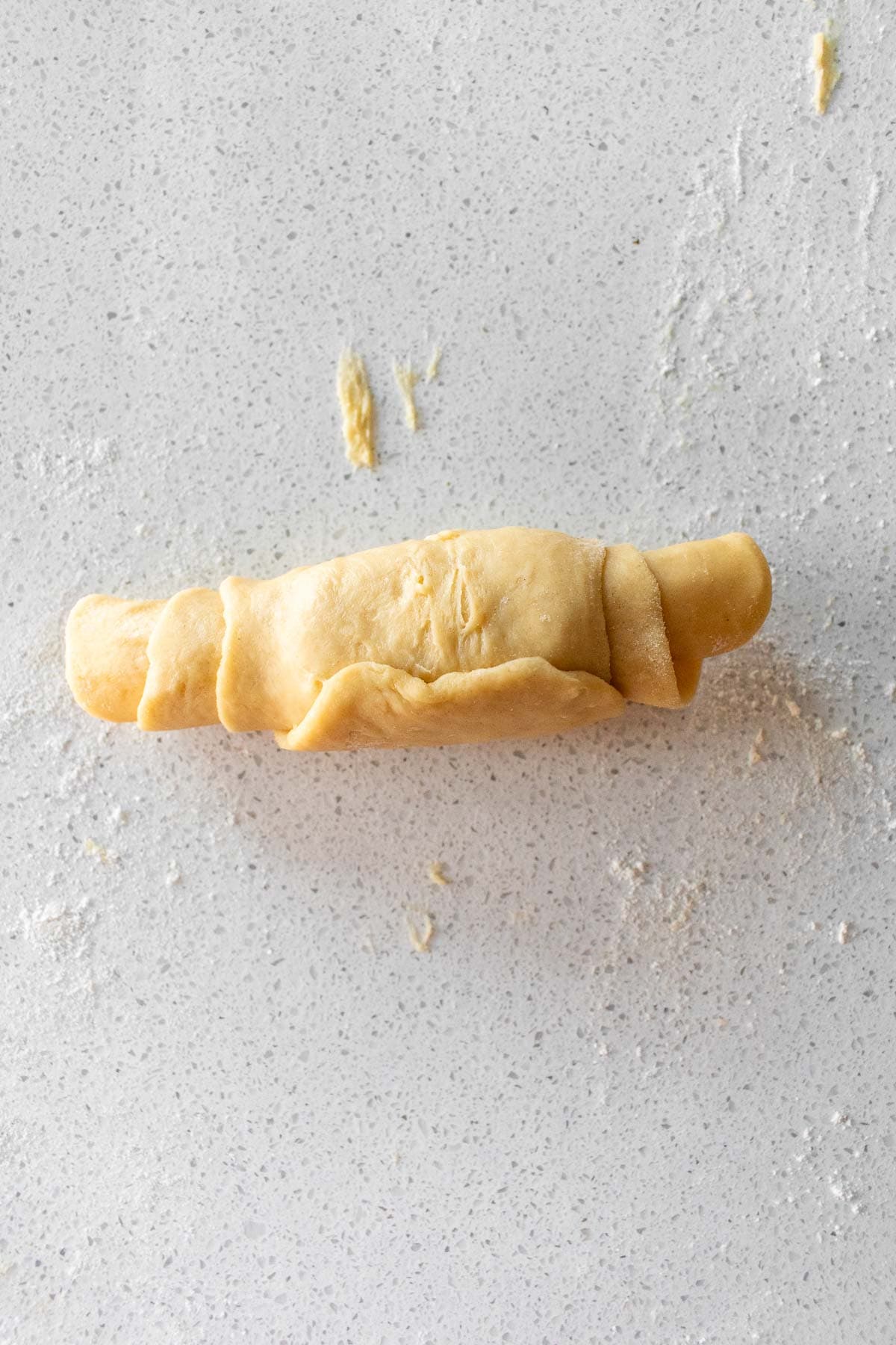 A rolled-up piece of soft bread dough on a light surface.