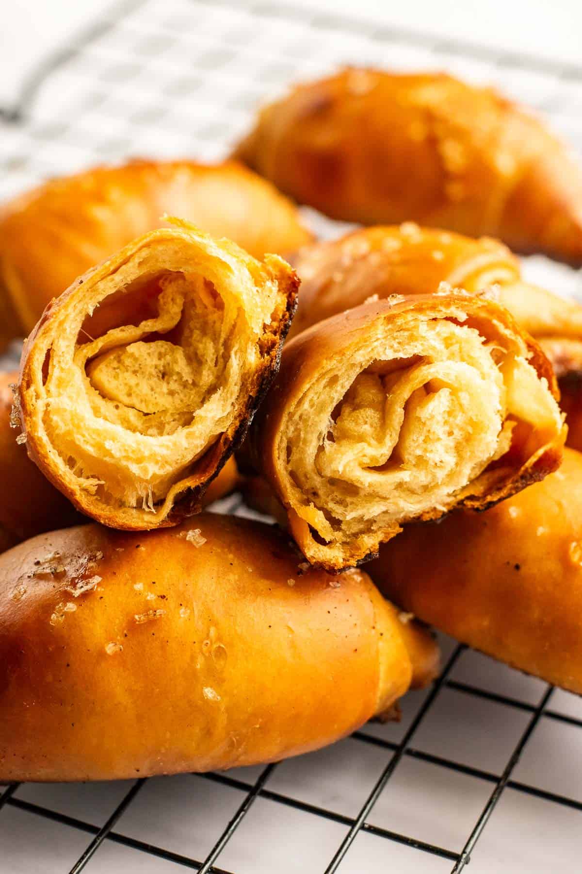 Dense, golden bread buns piled on a wire cooling rack on a light surface.
