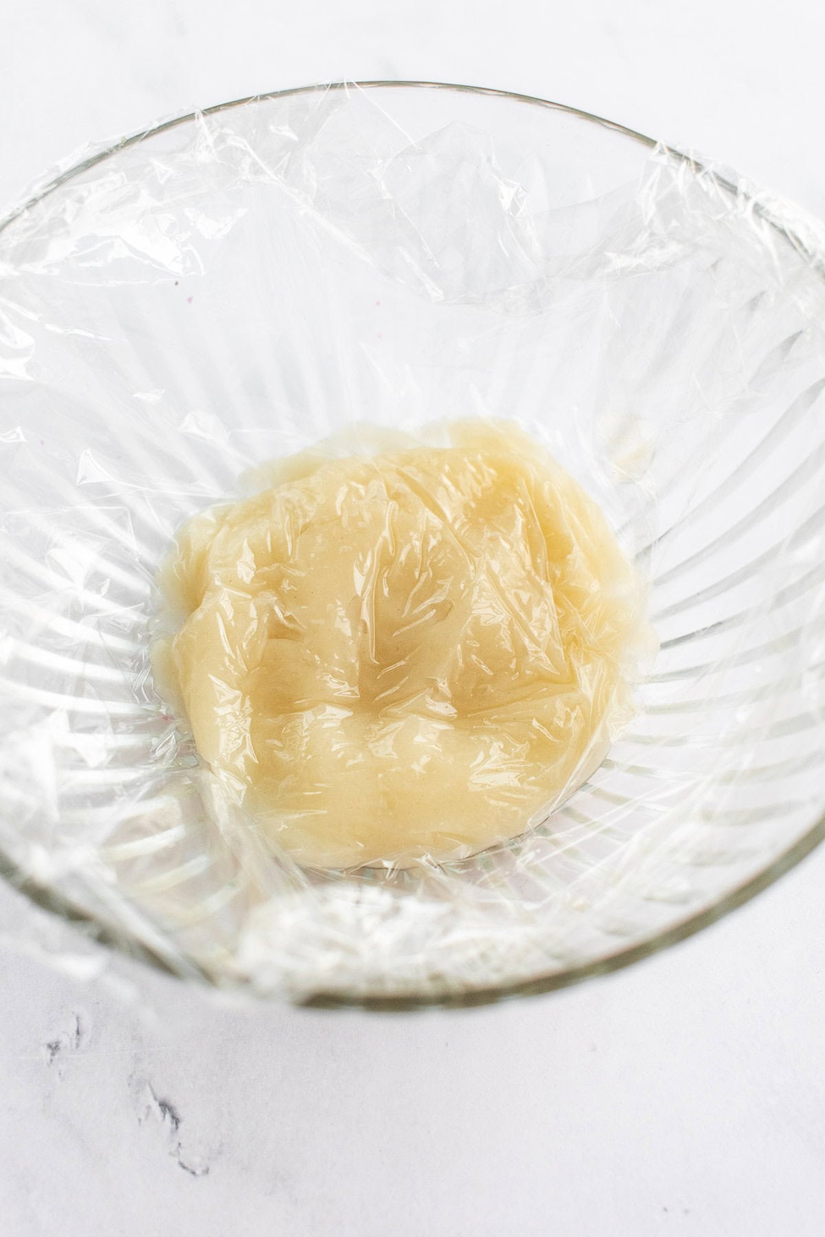 Tangzhong in a glass bowl covered with plastic wrap.