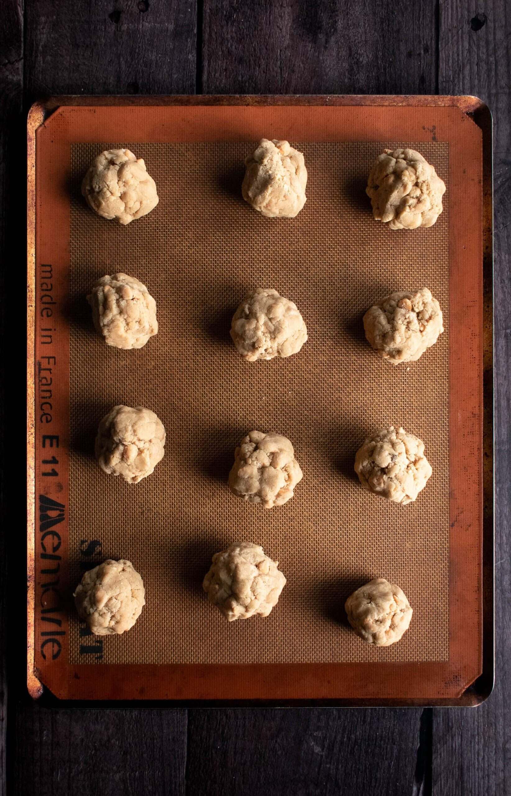 Two unbacked balls of cookie dough on a baking sheet.