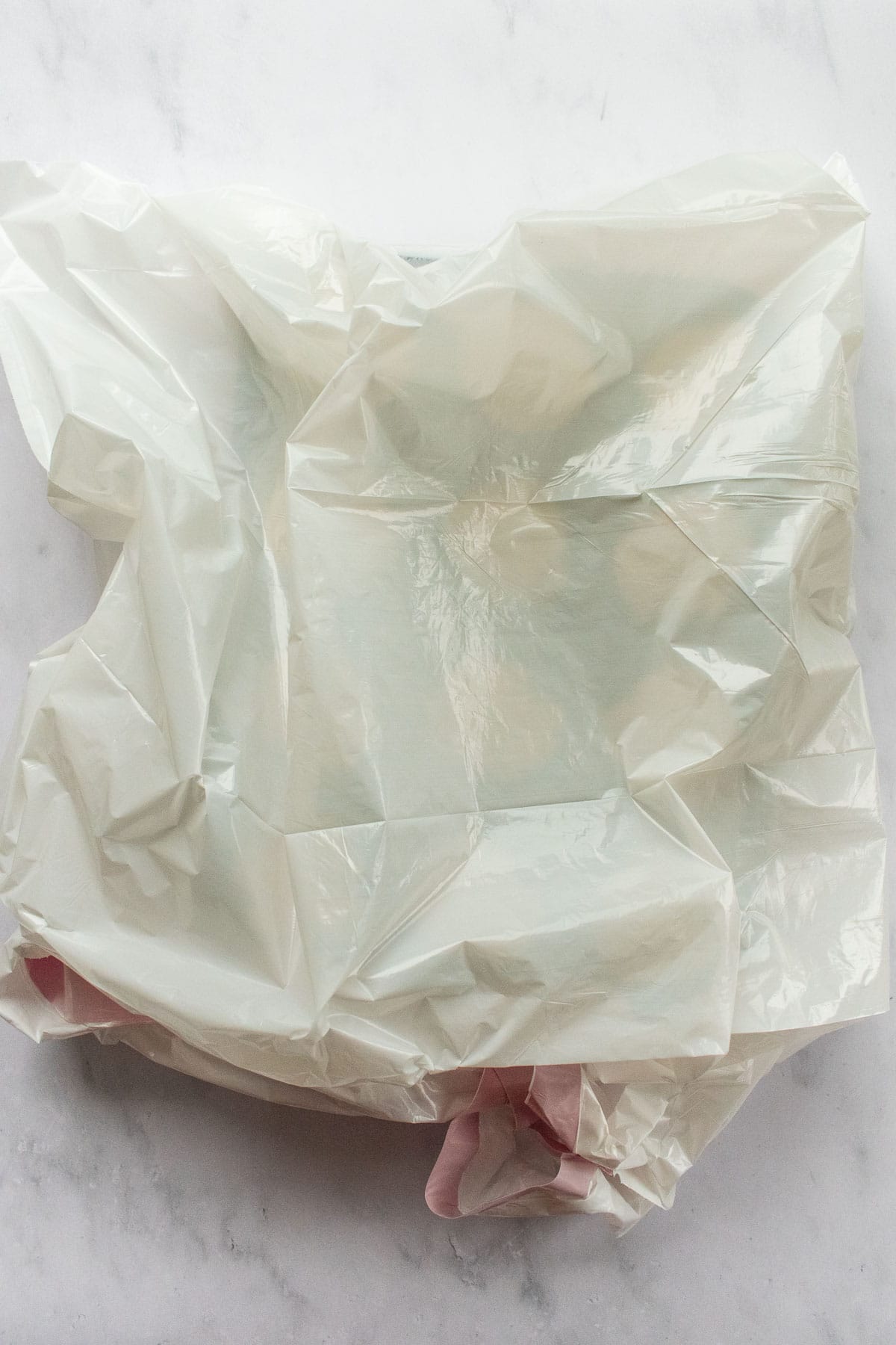 A white trash bag covering a muffin tin on a light table.