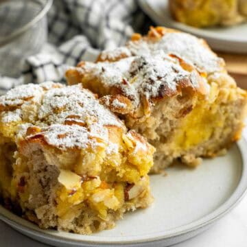 Two large pieces of focaccia filled with frangipane and topped with almonds and powdered sugar on a small grey plate.