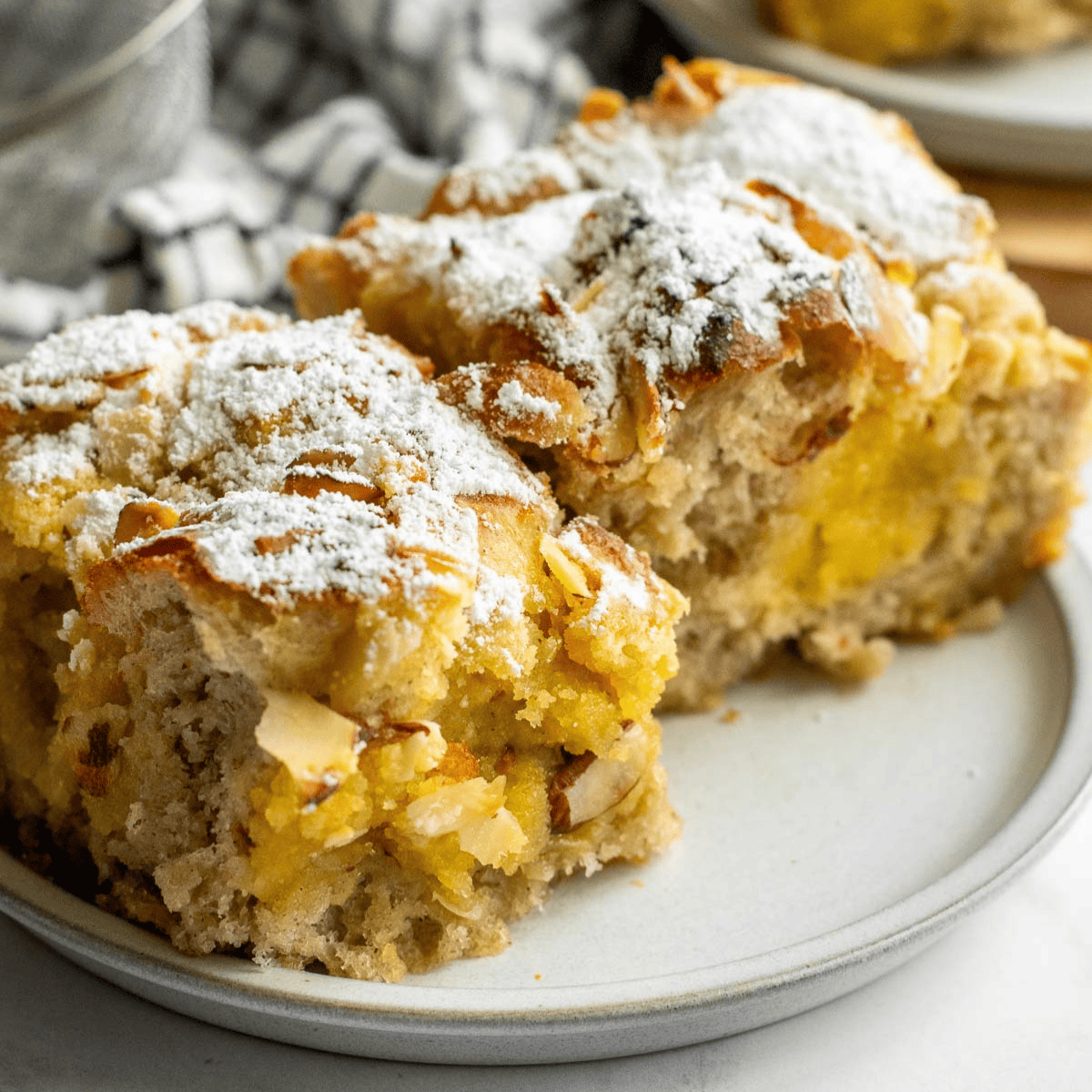 Two large pieces of frangipane focaccia topped with sliced almonds and powdered sugar.